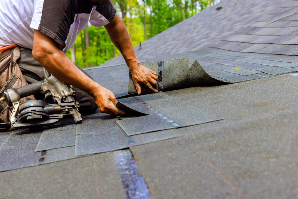 Roofer installing asphalt shingles on a residential roof.