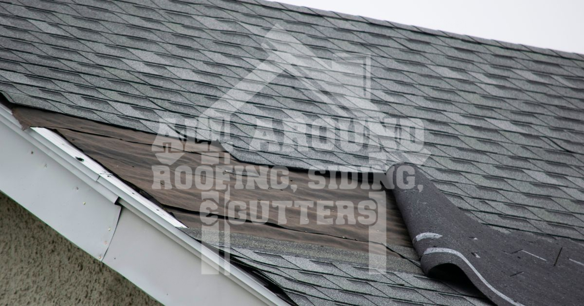Damaged roof shingles curling up from house roof showing storm damage