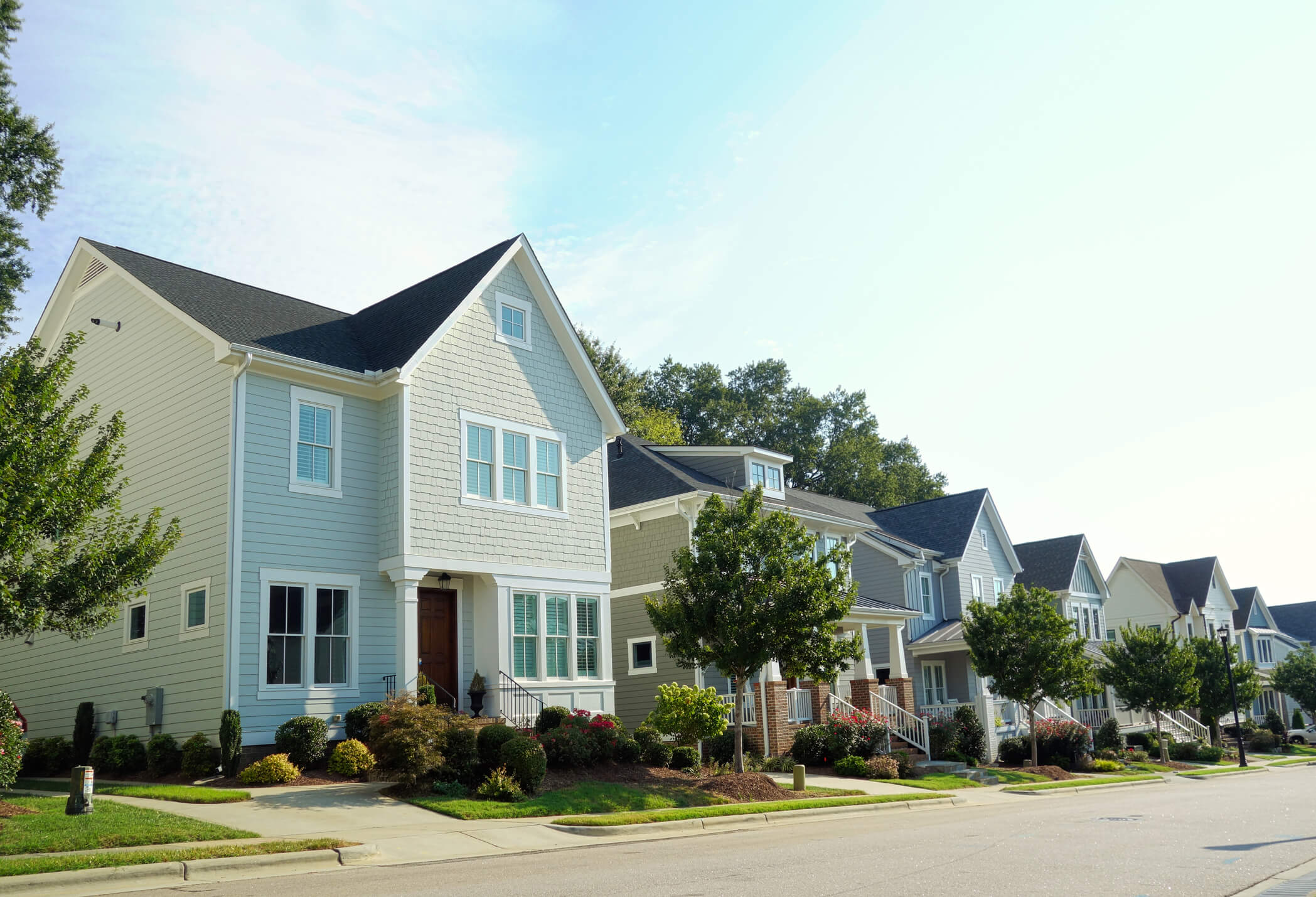 Modern suburban homes with colorful siding and front porches in residential neighborhood